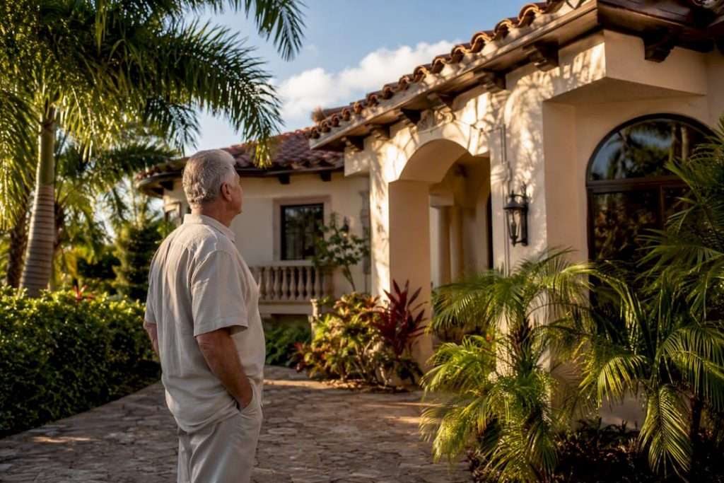Senior homeowner inspecting South Florida house exterior